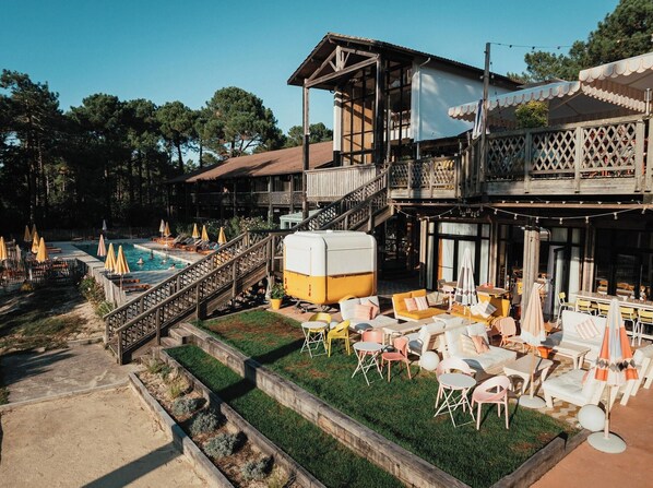 A resort with a pool, outdoor seating, and a multi-level building. - La Baignoire Hotel du Golf Lacanau (Lacanau)