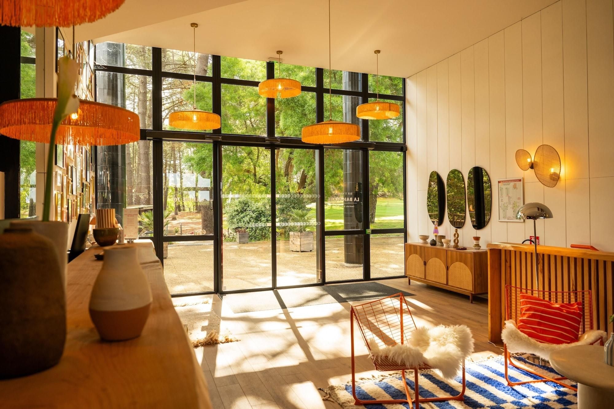A modern interior with large windows, a wooden reception desk, and a seating area with a patterned rug.