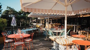Un espace de restauration en plein air avec des tables et des chaises, un bar et un coin salon abrité.