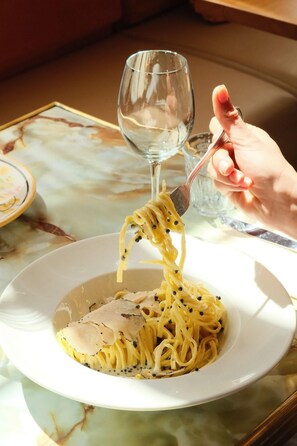 A plate of spaghetti with meatballs and black pepper, a fork lifting some spaghetti, and a wine glass in the background. - La Baignoire Hotel du Golf Lacanau (Lacanau)