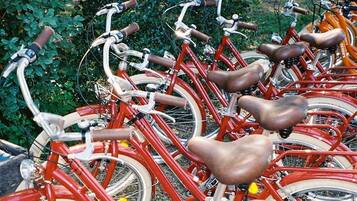 Une rangée de vélos rouges est garée sur un terrain recouvert de gravier, avec de la verdure en arrière-plan.