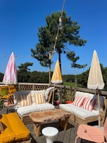 Una terraza con mobiliario exterior, incluyendo un sofá, sillas y una mesa, rodeada de sombrillas.