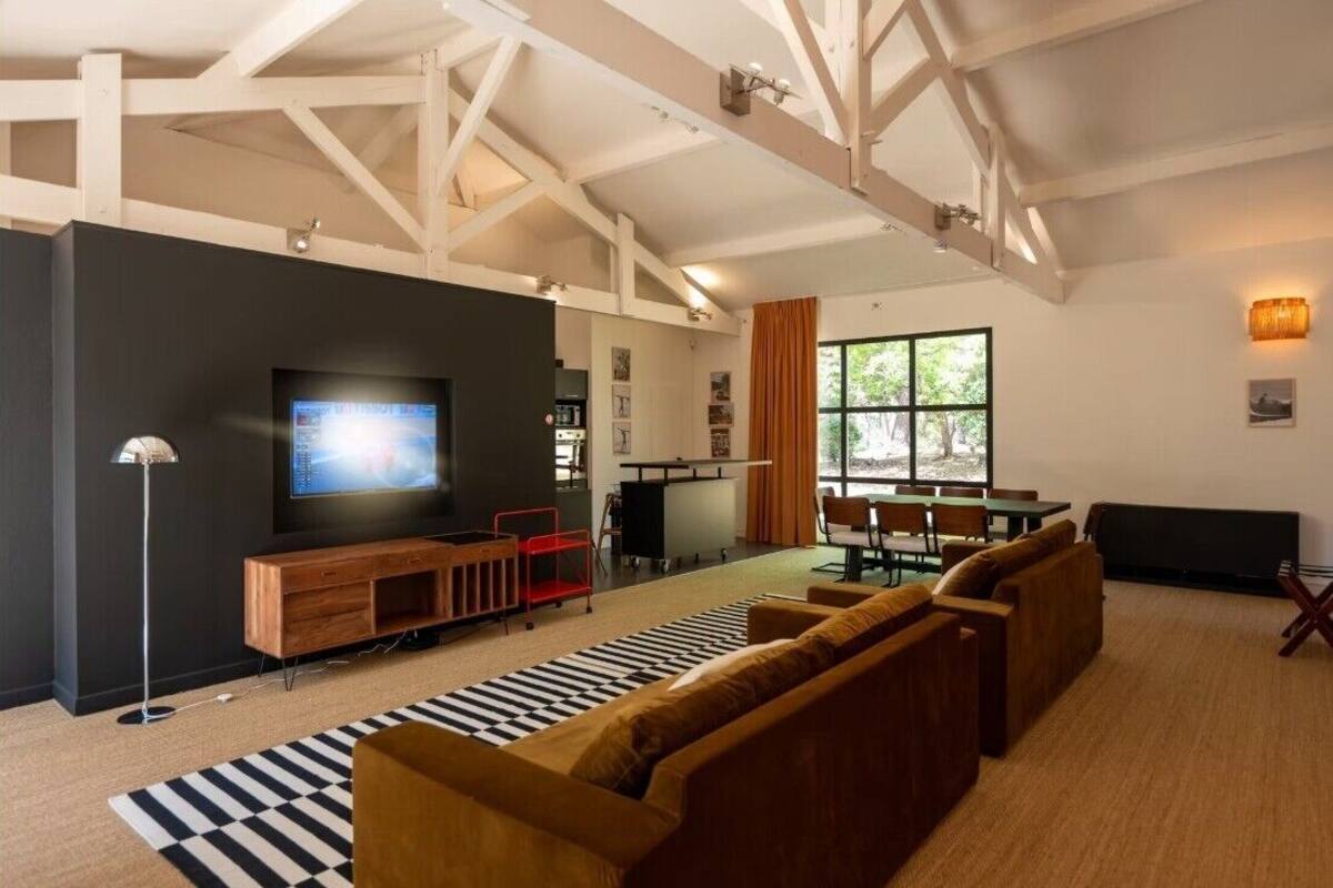 A modern living room with a large TV, wooden furniture, and a checkered rug.