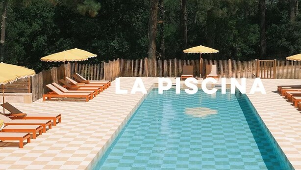 A swimming pool with lounge chairs and umbrellas, surrounded by a wooden fence. - La Baignoire Hotel du Golf Lacanau (Lacanau)
