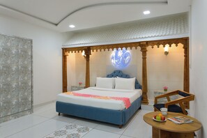 A bedroom with a bed, a round wall-mounted globe, a small table with fruits, and a chair. - Ginger Kheda (Kheda)