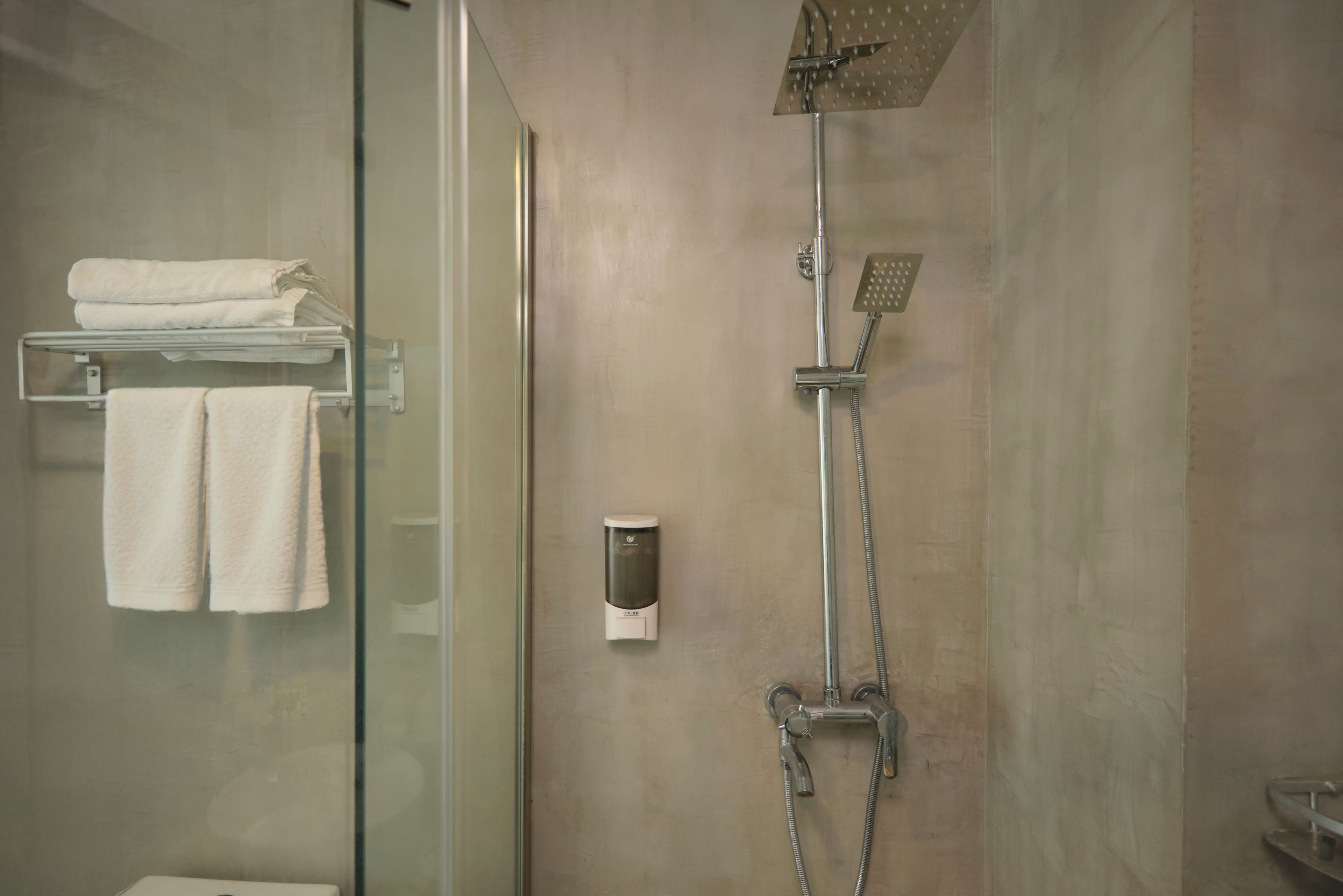 A modern shower with a handheld showerhead and a wall-mounted faucet.