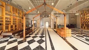 A spacious interior with a checkered floor, wooden shelving units, and a central wooden structure. - Yushan MJ Cultural Creative Theme (Huanggang)