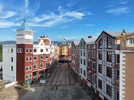 A narrow street lined with historic buildings, featuring a mix of architectural styles, including a prominent tower and a building with a distinctive facade.