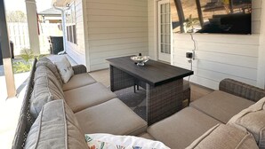 Un patio techado con un sofá, una mesa y un ventilador de techo.