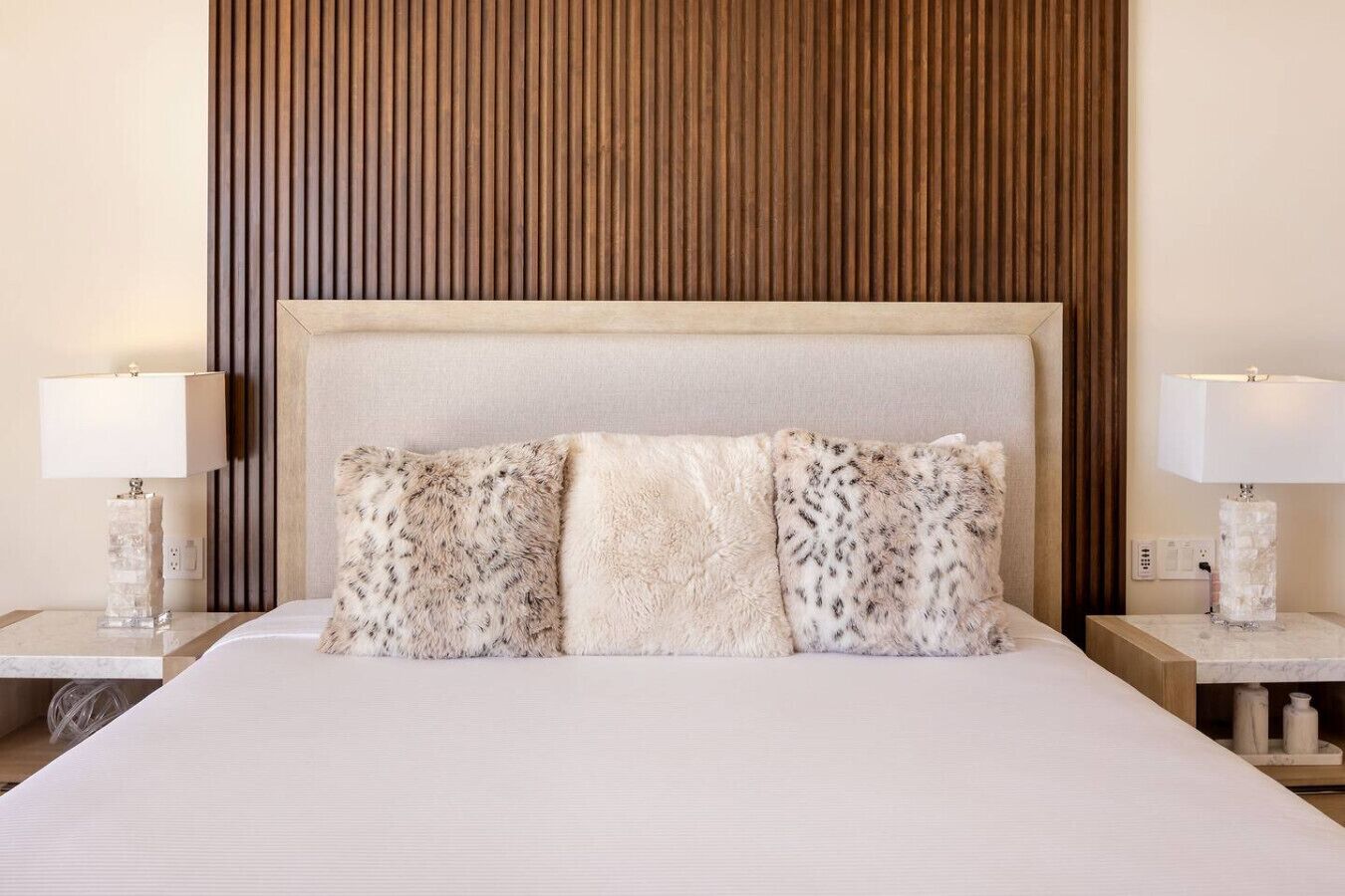 Une chambre d’hôtel avec un grand lit, deux tables de chevet et un mur recouvert de panneaux en bois.