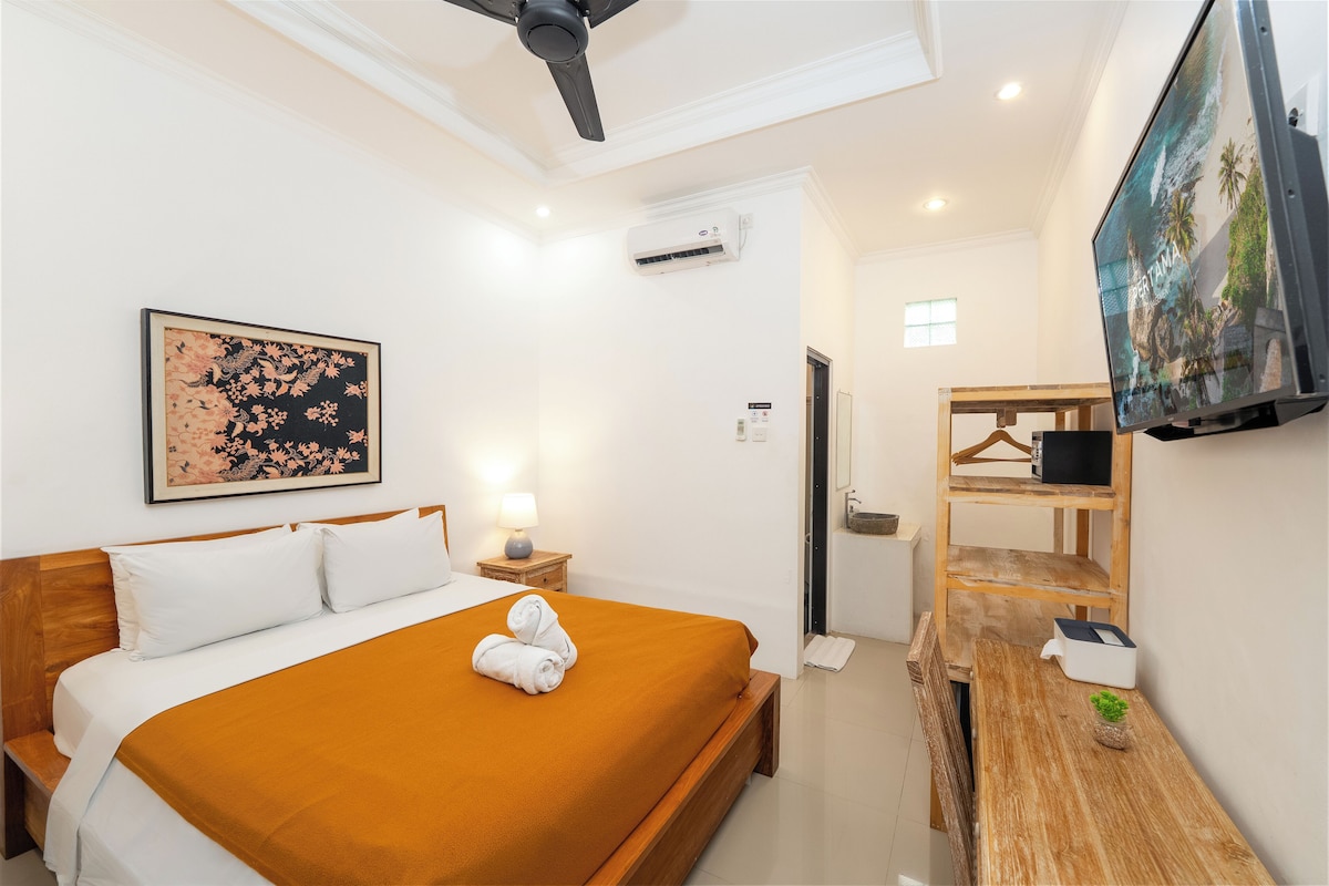 Une chambre d’hôtel avec un lit, une télévision, un banc en bois et un tableau au mur.