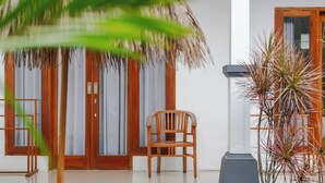 A wooden chair in front of a door with a glass panel, a potted plant, and a wooden bench. - Canggu Surf Paradise (Canggu)