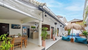 A spacious patio with a dining area, a pool, and potted plants. - Canggu Surf Paradise (Canggu)