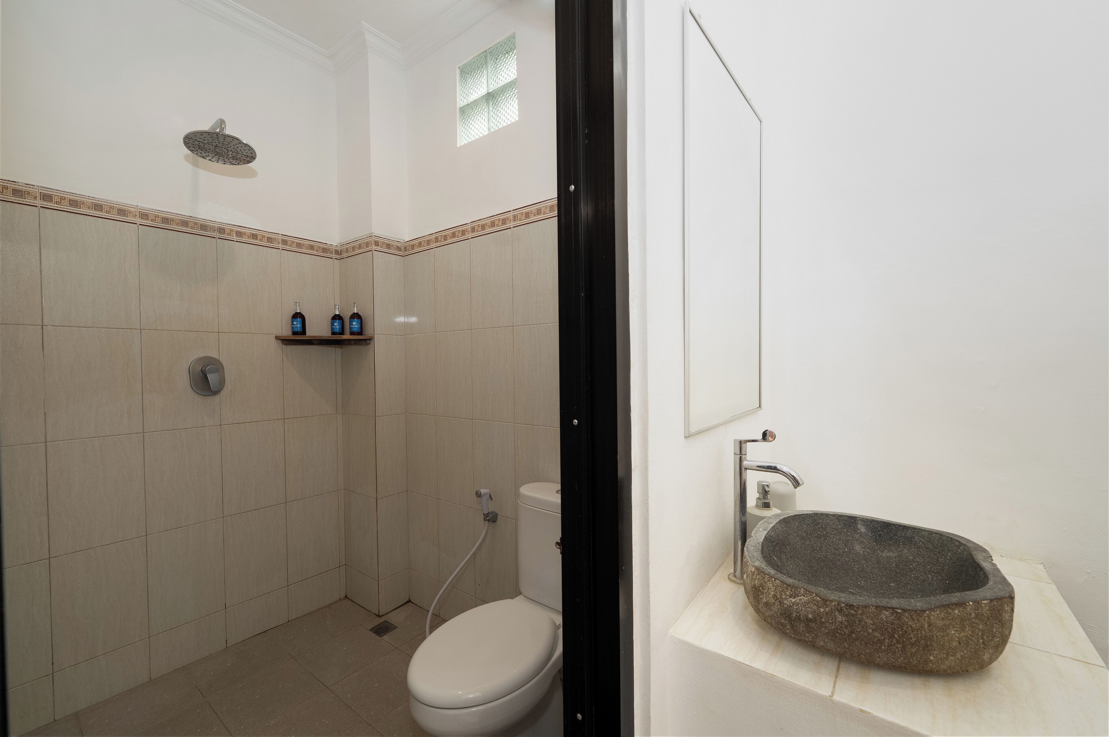 A bathroom with a shower, toilet, and a stone sink.