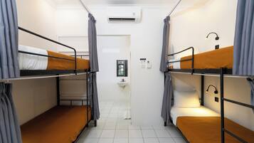 A dormitory room with bunk beds, a sink, and an air conditioning unit.