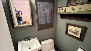 Un baño con lavamanos, inodoro y cuadros en la pared.