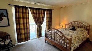 Un dormitorio con cama de madera, una silla, una ventana con cortinas e imagen en la pared.