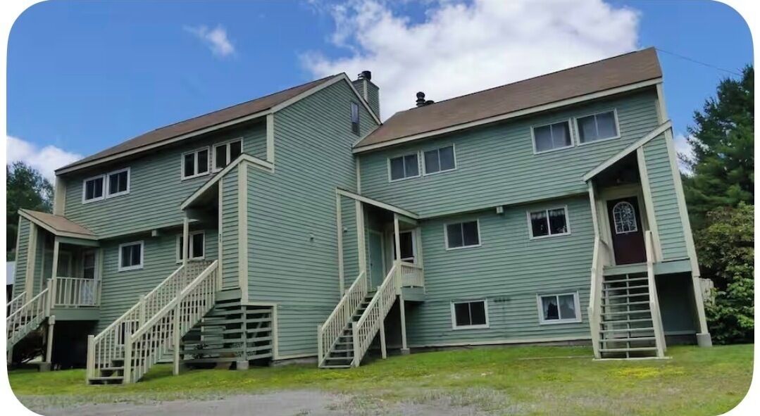 A two-story building with a central staircase and a small porch area.