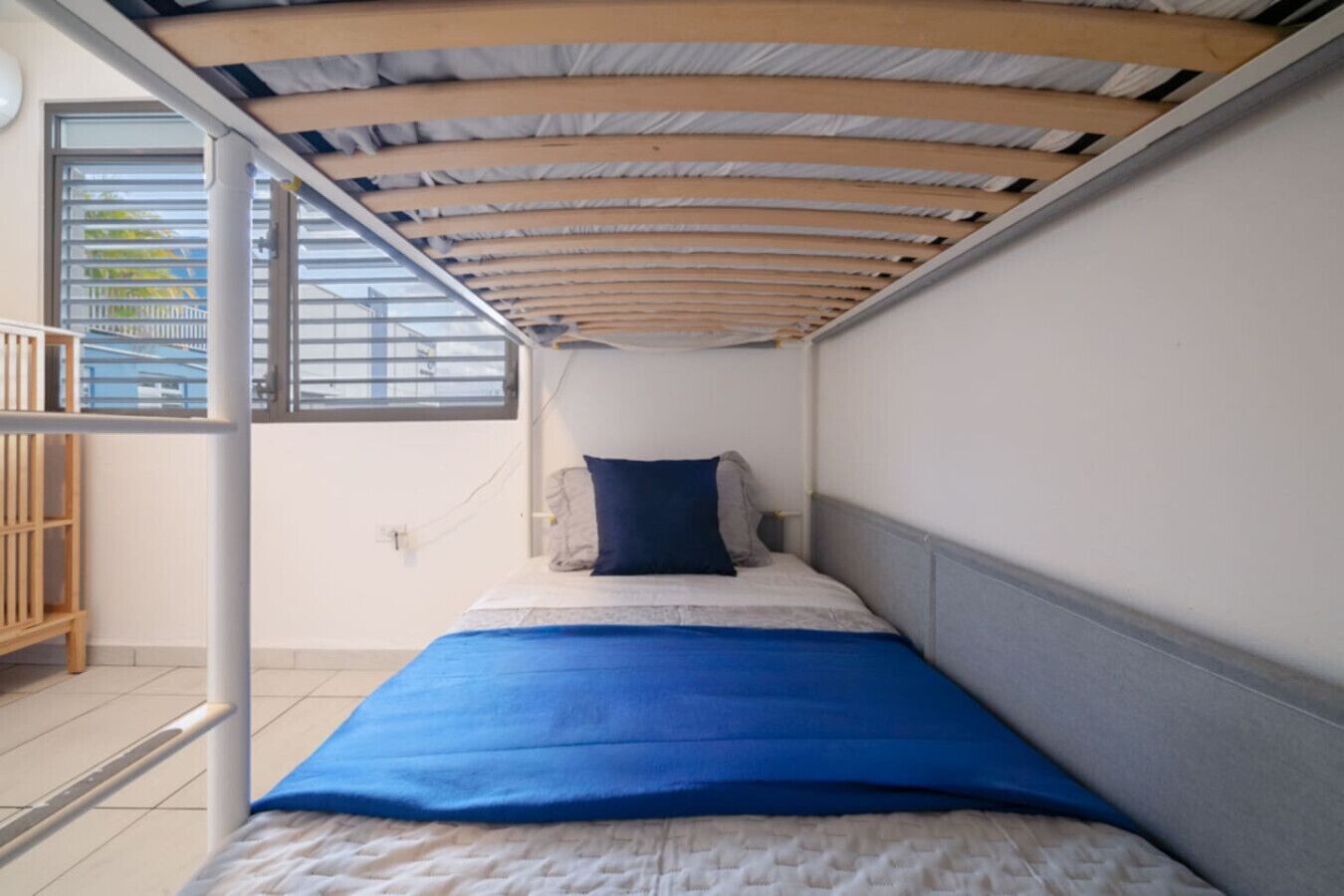 Una stanza piccola con un letto, una finestra e una struttura in legno sopra il letto.