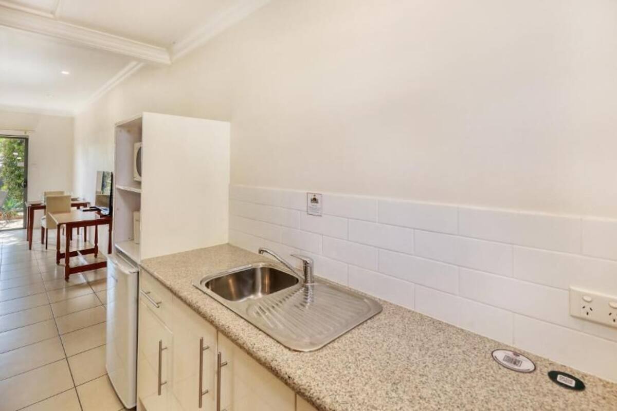 A modern kitchen with a granite countertop, stainless steel sink, and white tiled backsplash.