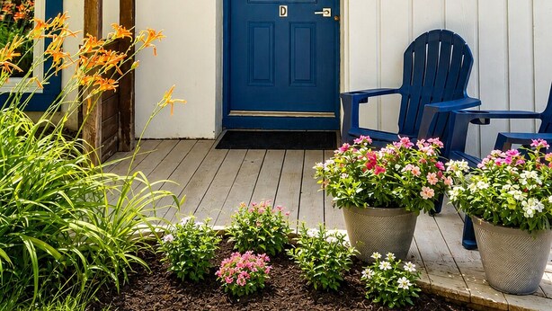 Une maison avec une porte bleue, un porche en bois et des plantes en pot.