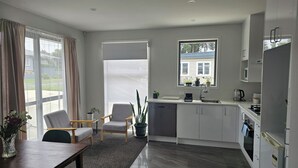 Eine moderne Küche mit Essbereich, großen Fenstern und Blick auf ein Haus.