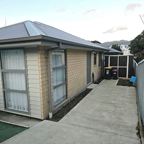 A single-story house with a brick facade, large windows, and a metal roof. - Entire House - 2 Bedroom Bungalow (Lower Hutt)