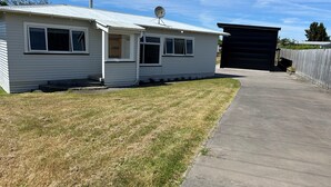 Ein eingeschossiges Haus mit Metalldach, Satellitenschüssel und Garage.
