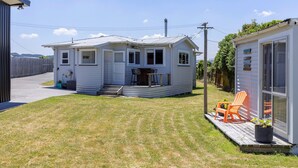 Ein kleines, eingeschossiges Haus mit Veranda und einer kleinen Terrassenfläche.