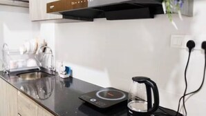 Una cocina moderna con una cocina por inducción negra, una cafetera de vidrio y un lavamanos de acero inoxidable.