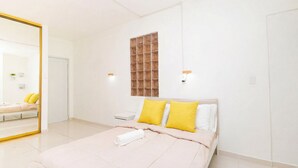Une chambre à coucher avec un lit, un miroir, une fenêtre et une table de chevet.