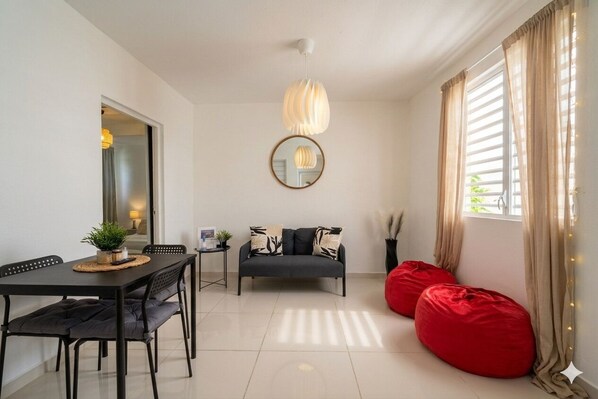 Una sala moderna con una mesa de comedor, sofá y sillones de mimbre rojo.