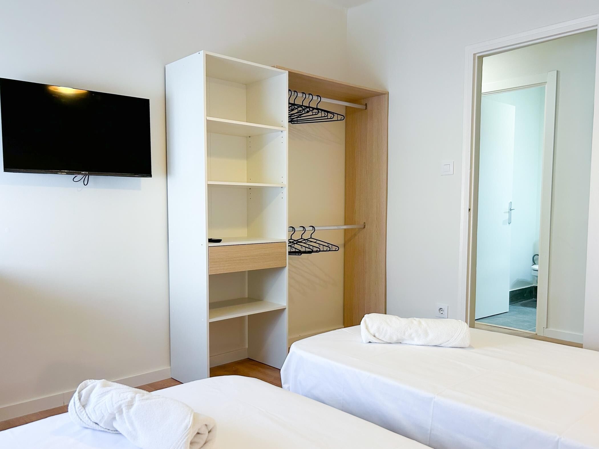 Ein Hotelzimmer mit Bett, Schrank, Spiegel und Fernseher.