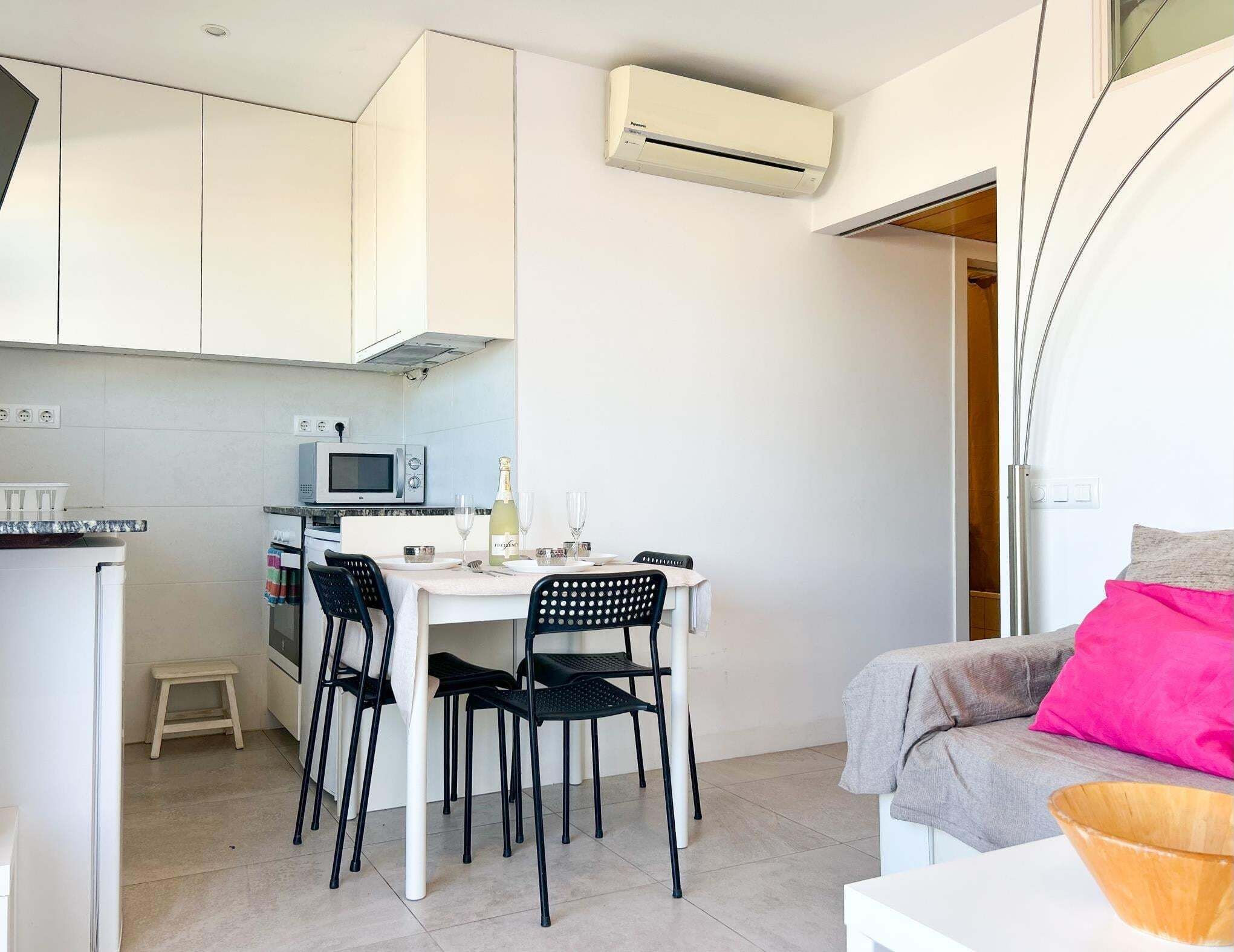 Un espacio habitable compacto con kitchenette, comedor y zona de estar.