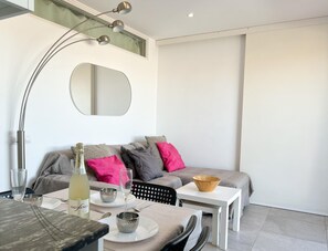 Een moderne woonkamer met een bank, een eettafel en een grote spiegel.