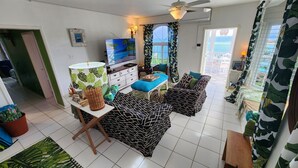 Een woonkamer met een televisie, een bank, een salontafel en een raam met gordijnen.