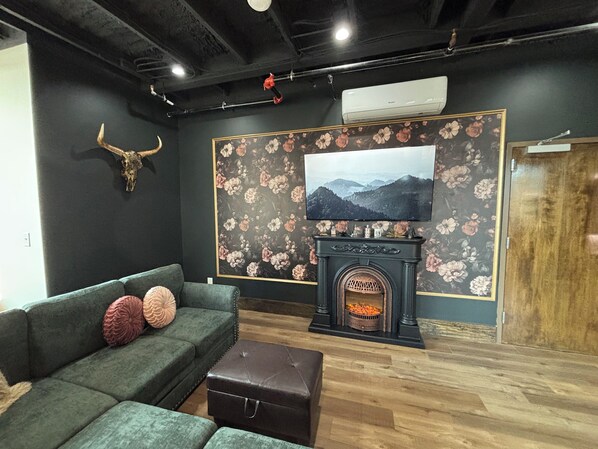 A living room with a green sofa, a fireplace, and a TV mounted on the wall.