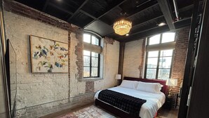 Ein Schlafzimmer mit einem großen Bett, einem farbenfrohen Teppich, einer Kristallleuchtre und einem Bild an der Wand.
