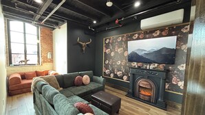 Ein modernes Wohnzimmer mit einer Eckcouch, einem Kamin und einem großen Fernseher.