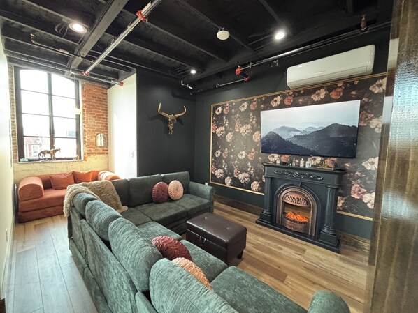 Una sala de estar moderna con un sofá modular, una chimenea y un televisor grande.