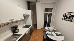 A compact kitchen with a stove, sink, and a dining area with a table and chairs. - Modern 65m² apartment with parking space + balcony (Chemnitz)