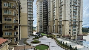 A high-rise residential building complex with multiple balconies, a central courtyard with circular planters, and a view of a body of water.