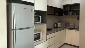 A modern kitchen with white cabinets, a stainless steel refrigerator, a microwave, and a sink.