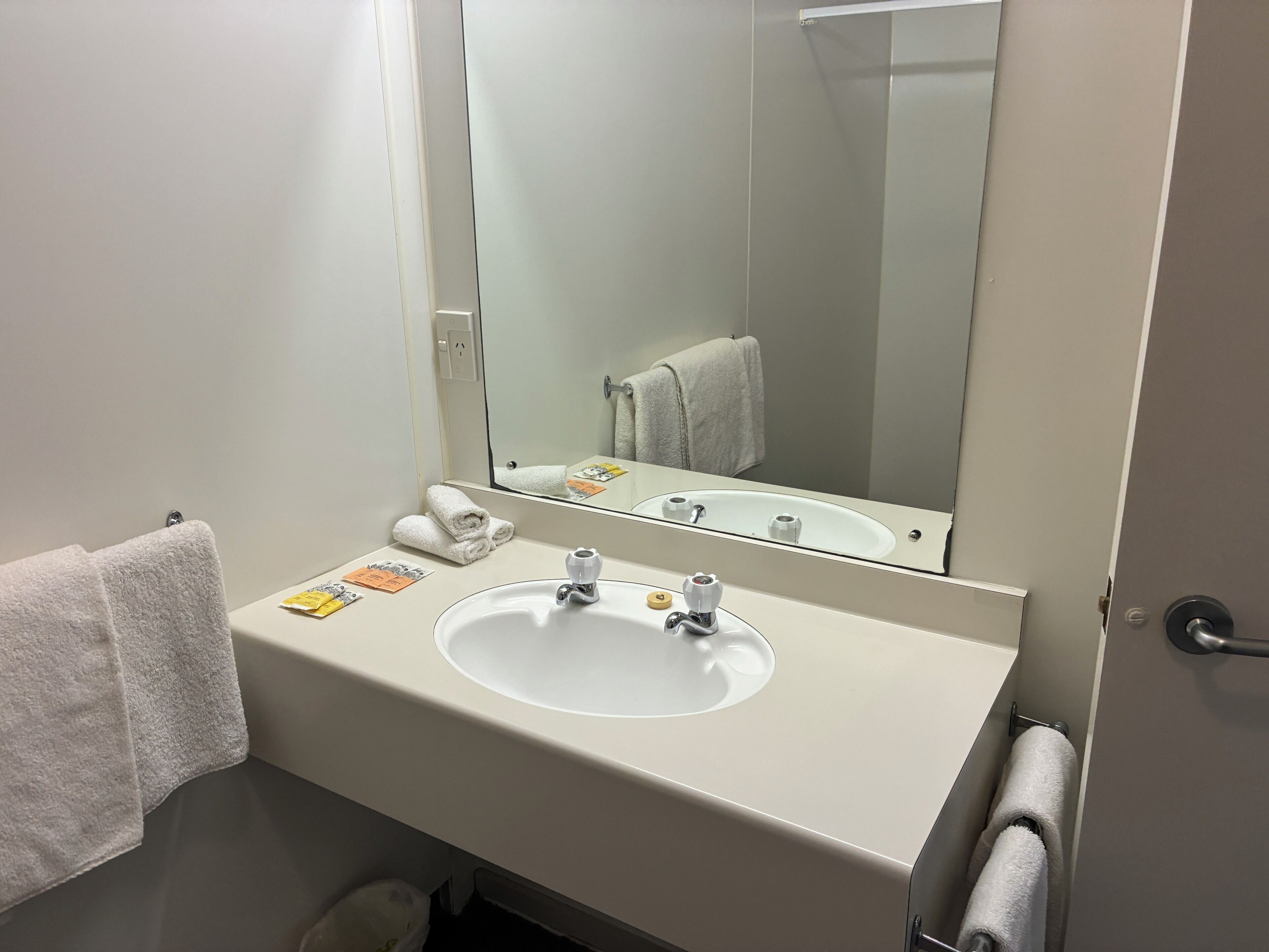 A bathroom with a white sink, a mirror, and a towel rack.