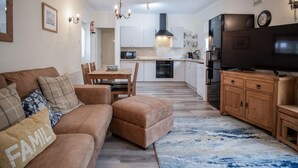 Ein modernes Wohnzimmer mit einem braunen Sofa, einem Couchtisch aus Holz und einem Fernseher auf einer Holzkommode.