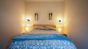 Ein Schlafzimmer mit einem Bett, zwei Wandlampen und einer blauen Bettdecke.