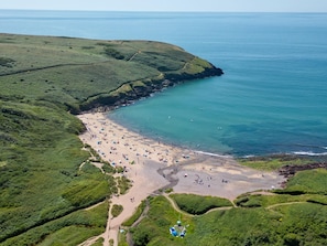 An aerial view of a beach with a clear path leading to the water, surrounded by greenery.