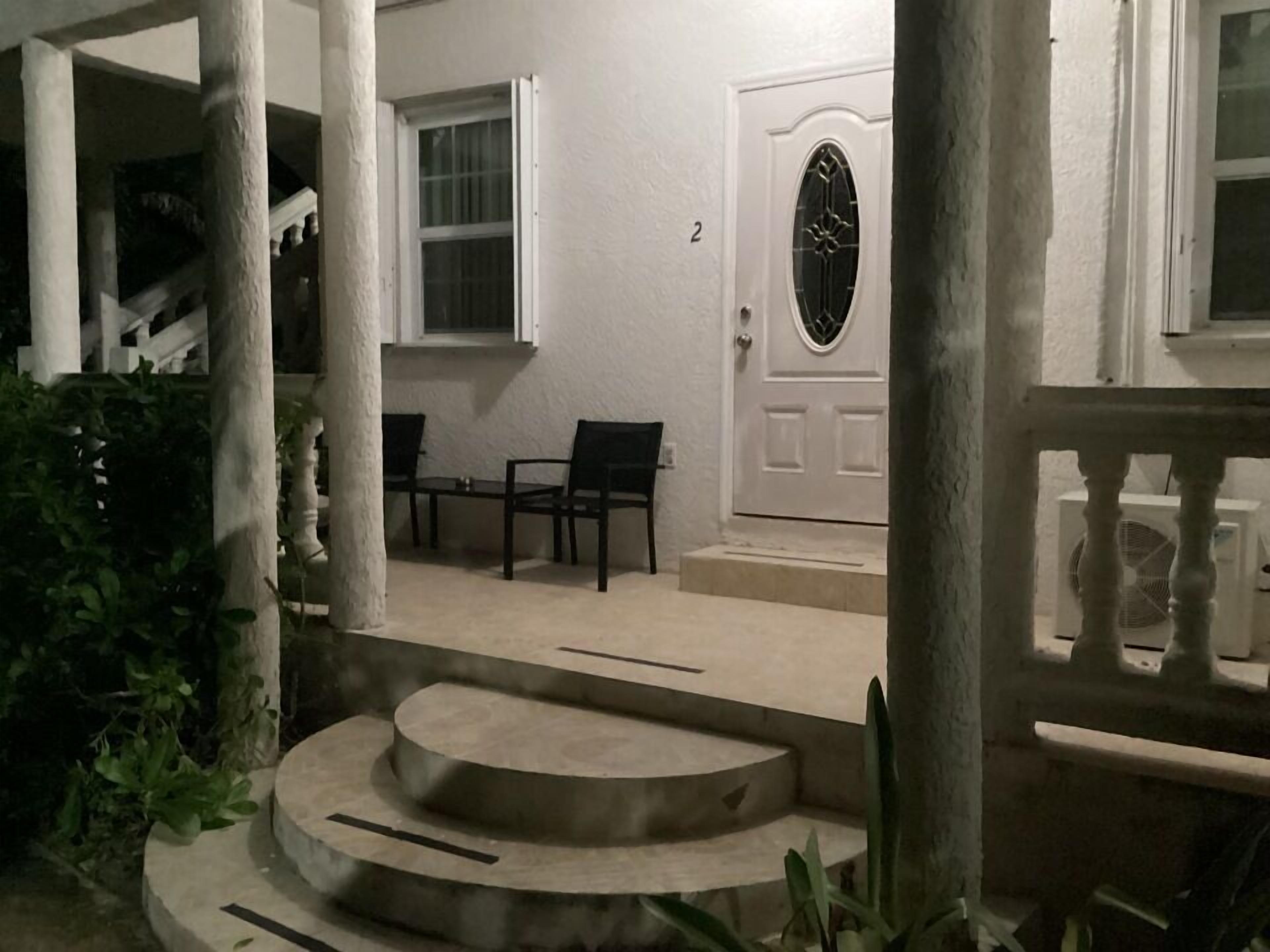 A staircase leading to a porch with two chairs and a door with a decorative glass panel.