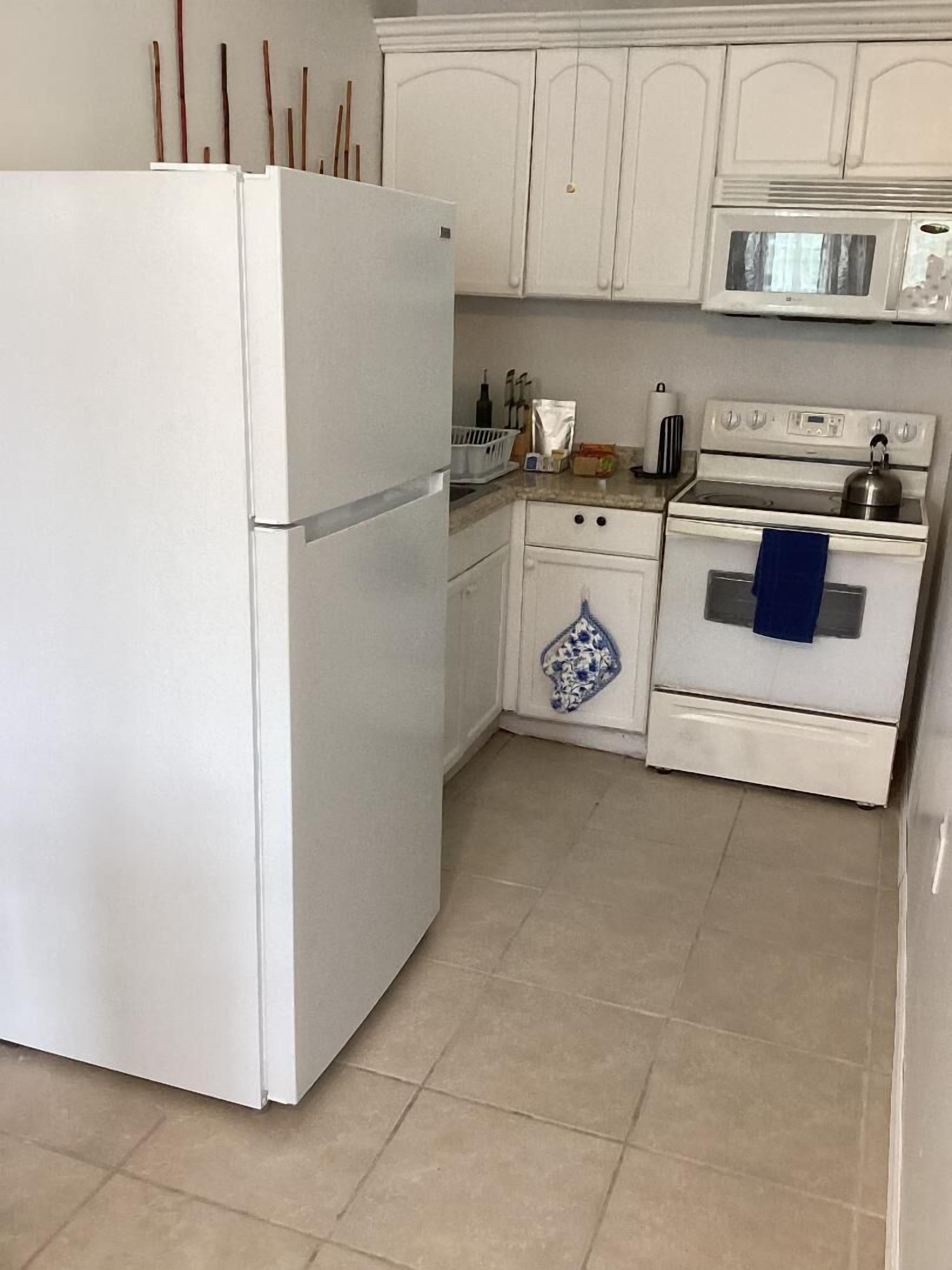 A kitchen with white cabinets, a refrigerator, a microwave, and an oven.