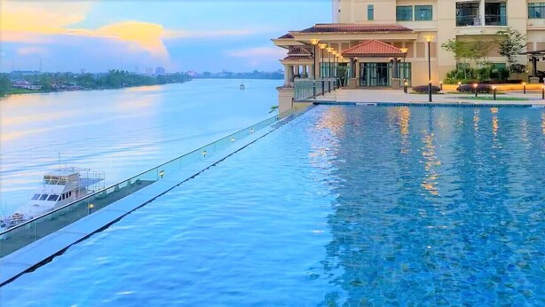 Ein Schwimmbad mit Blick auf einen Fluss und ein Gebäude mit einem Balkon.